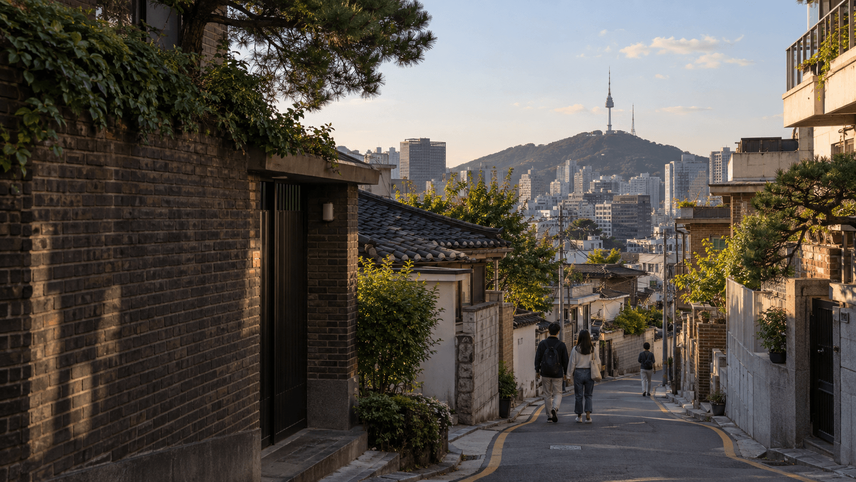 An illustrated Seoul neighborhood street, with people walking downhill and Namsan in the distance