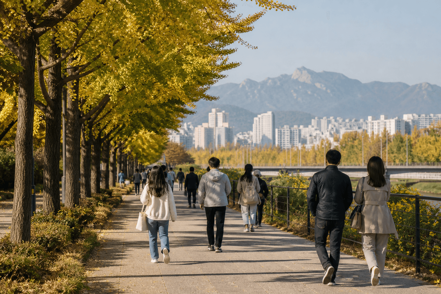 People walking beneath golden ginkgo trees with Seoul and its mountains beyond