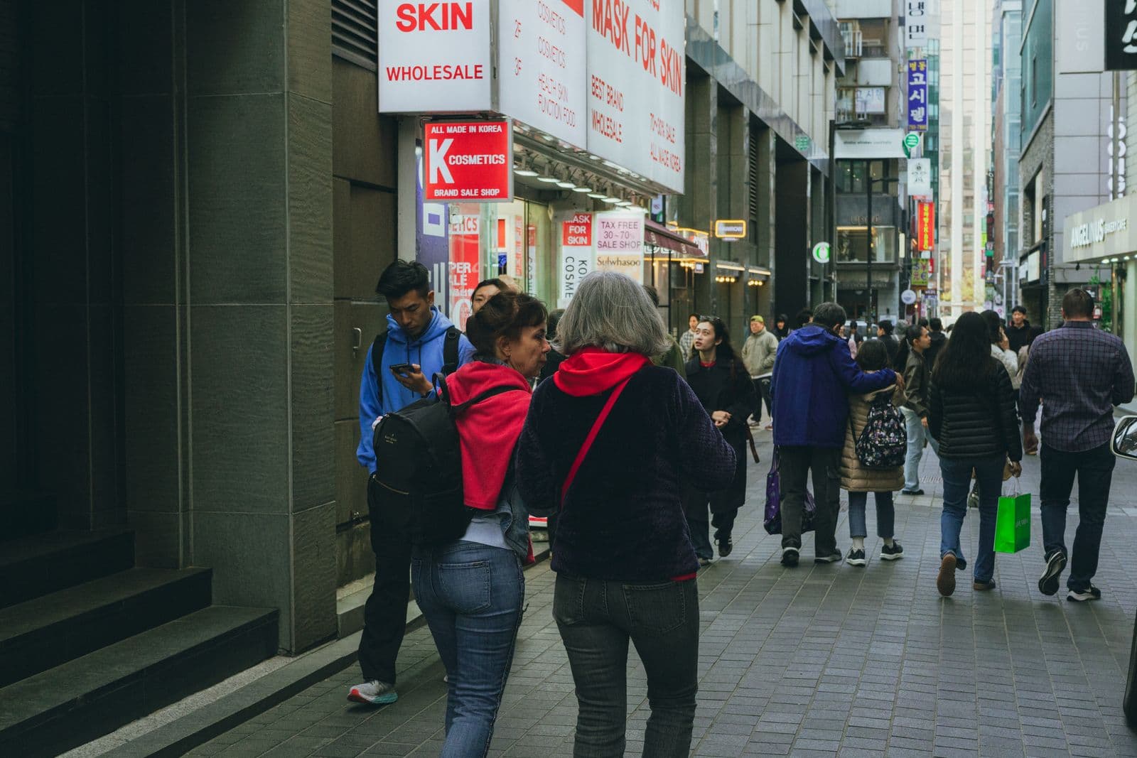 Shoppers walking past cosmetics and tax-free storefronts on a busy Myeongdong street